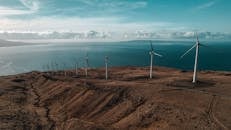 Aerial view of a coastal wind farm under a blue sky, symbolizing renewable energy and sustainability.