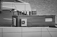 Black and white image showcasing a modern rooftop with air conditioning and ventilation units by the waterfront.