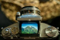Close-up of a vintage camera focusing on a mountain landscape visible in the viewfinder.