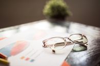 pexels photo 7947706 7947706 Eyeglasses placed on a business document with financial graphs and charts.