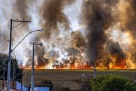 pexels photo 12027855 12027855 Rural landscape with a field engulfed in flames and thick smoke rising under a clear sky.