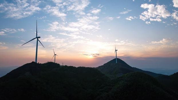 2026 Mid-Year Review: The Sustainability Wins That Matter, and the Setbacks We Can’t Ignore Silhouetted wind turbines on a hilly landscape during sunset, highlighting renewable energy.