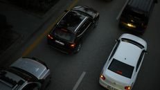 Aerial shot showing multiple cars driving on a city road during the evening, illustrating urban traffic.