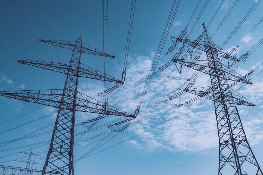 pexels photo 27180835 27180835 High voltage transmission towers stretch across a clear blue sky, symbolizing energy and industry.