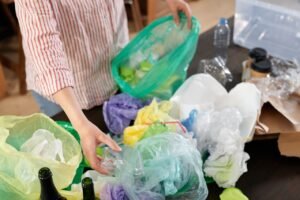 Nearly 60,000 Tonnes of Plastic Avoided a Year: Measuring the UK Bag Levy's Impact Person sorting various recyclable plastics and bottles indoors.